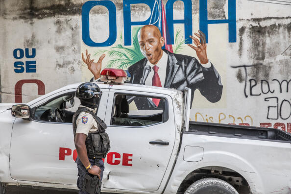 A police officer stands by a wall painted with a mural of late Haitian President Jovenel Moise, Port-au-Prince , July 15, 2021. (Valerie Baeriswyl/AFP)