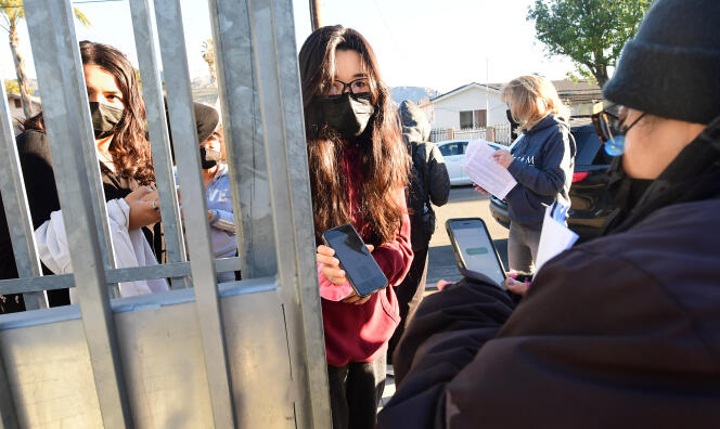 A student shows her negative Covid-19 test result at the entrance to Olive-Vista Middle School in Sylmar, California, January 11, 2022.