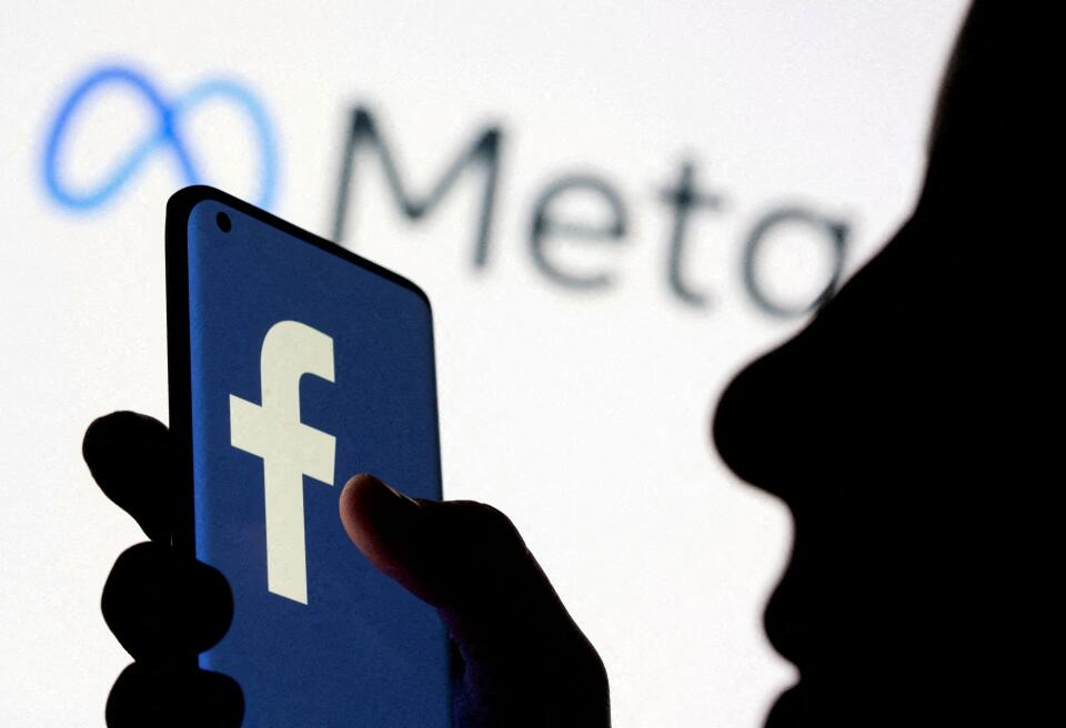 FILE PHOTO: A woman holds smartphone with Facebook logo in front of a displayed Facebook's new rebrand logo Meta in this illustration picture taken October 28, 2021. REUTERS/Dado Ruvic/Illustration/File Photo