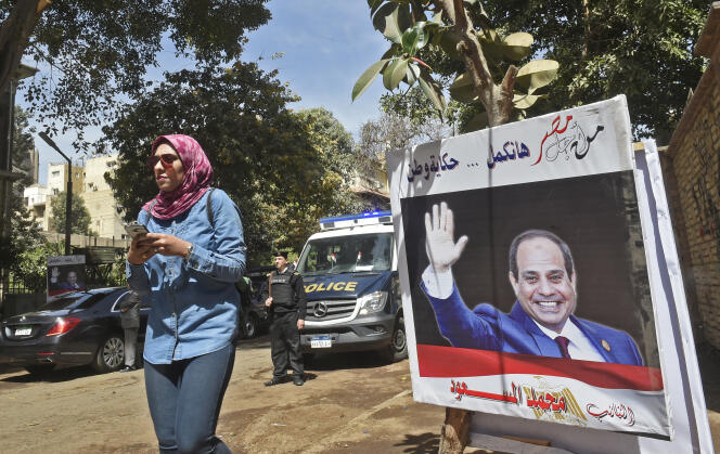 An Egyptian woman walks past a poster of President Abdel Fattah Al-Sissi in March 2018 in Cairo.