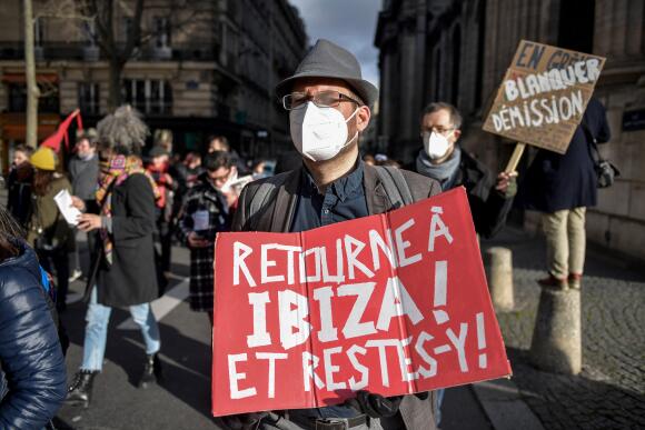 A man holds a placard reading in French "Go back to Ibiza ! And stay there !" as he takes part in a demonstration as part of a national day of strike called by French teachers and school staff unions to protest against the government's handling of the Covid-19 crisis in schools in Paris on January 20, 2022. - France's Education minister faced calls to resign on January 18, 2022 after regretting the "symbolism" of a holiday escape to Ibiza, where he announced a strict Covid testing protocol for students that sparked a fierce backlash from teachers. (Photo by JULIEN DE ROSA / AFP)