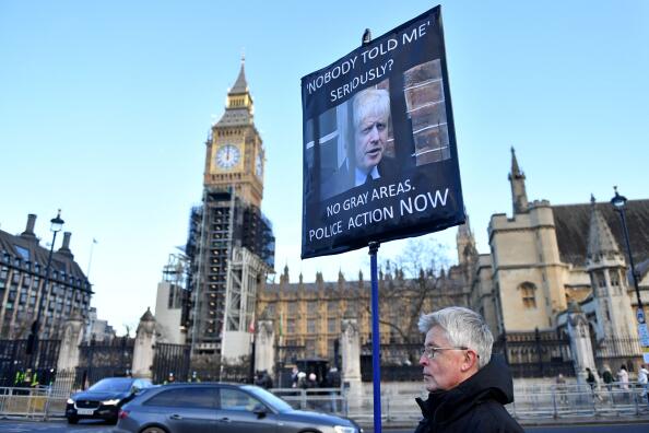 A demonstrator holds a placard reading "Nobody Told Me" as they protest outside of the Houses of Parliament in Westminster, central London on January 19, 2022. British Prime Minister Boris Johnson on Wednesday suffered an embarrassing defection from his Conservative party over revelations of lockdown-breaching events in Downing Street, but vowed to fight on. (Photo by JUSTIN TALLIS / AFP)