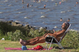 A man sunbathes along the coast of the Rio de la Plata estuary in Vicente Lopez, near Buenos Aires, on January 13, 2022, as an intense heat wave affects the metropolitan area of the Argentine capital and its surroundings. (Photo by Alejandro PAGNI / AFP)