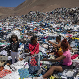Women search for used clothes amid tons discarded in the Atacama desert, in Alto Hospicio, Iquique, Chile, on September 26, 2021. - EcoFibra, Ecocitex and Sembra are circular economy projects that have textile waste as their raw material. The textile industry in Chile will be included in the law of Extended Responsibility of the Producer (REP), forcing clothes and textiles importers take charge of the waste they generate. (Photo by MARTIN BERNETTI / AFP)