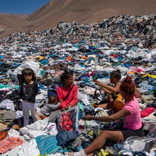 Women search for used clothes amid tons discarded in the Atacama desert, in Alto Hospicio, Iquique, Chile, on September 26, 2021. - EcoFibra, Ecocitex and Sembra are circular economy projects that have textile waste as their raw material. The textile industry in Chile will be included in the law of Extended Responsibility of the Producer (REP), forcing clothes and textiles importers take charge of the waste they generate. (Photo by MARTIN BERNETTI / AFP)