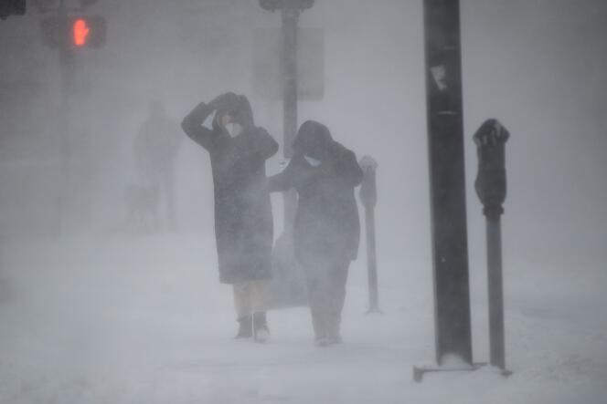 Des passants essaient de se protéger du blizzard, à Boston, samedi 29 janvier 2022.