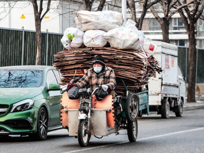 Un travailleur migrant transportant du carton recyclable, à Pékin, le 20 janvier 2022.
