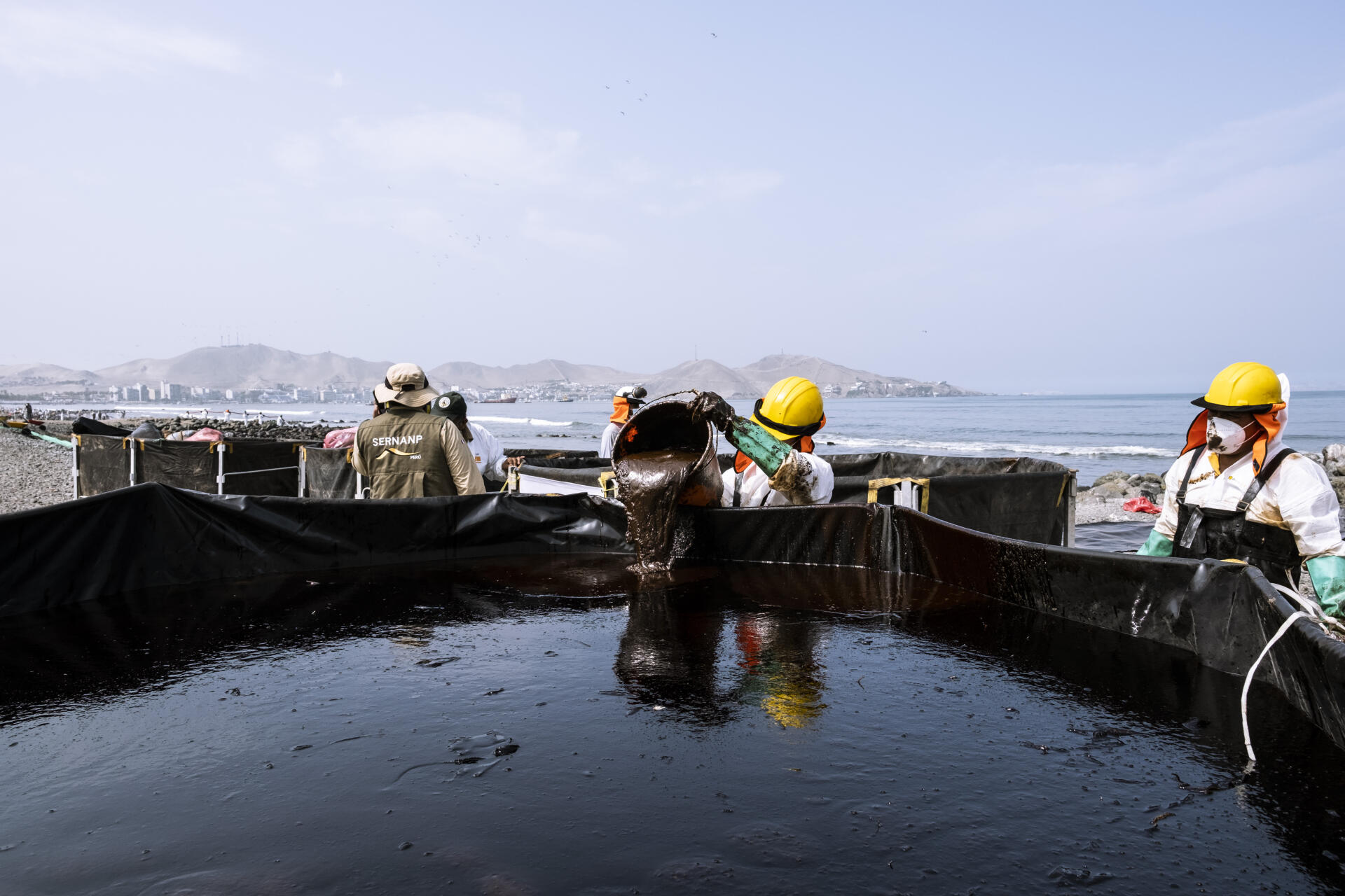 La playa Ancón se limpia con algunas herramientas y el combustible se recoge con palas, cepillos y baldes.  Norte de Lima, Perú, 27 de enero de 2022.