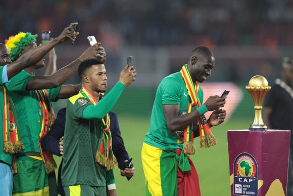 Senegal's players celebrate and take pictures of the trophy after winning the Africa Cup of Nations (CAN) 2021 final football match between Senegal and Egypt at Stade d'Olembe in Yaounde on February 6, 2022. (Photo by Kenzo TRIBOUILLARD / AFP)