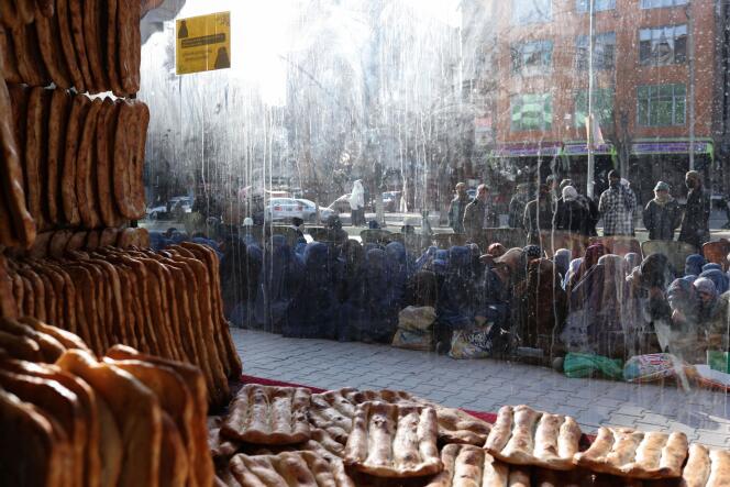 Des Afghans sont assis par terre devant une boulangerie en attendant de recevoir une ration de pain, à Kaboul, le 31 janvier 2022.