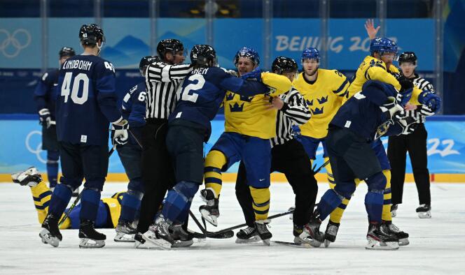 Bagarre générale entre les hockeyeurs finlandais (en bleu) et suédois (en jaune) lors d’un match du tour préliminaire du tournoi de hockey, à Pékin, le 13 février 2022.