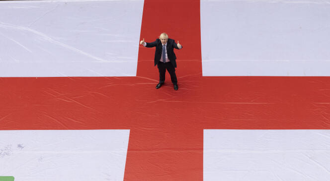 Le premier ministre Boris Johnson devant le 10 Downing Street, à Londres, foulant un drapeau géant anglais avant le match de quart de finale de l’Angleterre contre l’Ukraine, le 3 juillet 2021.