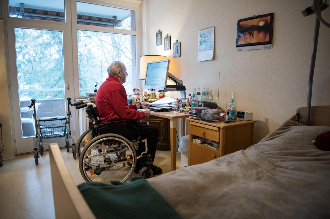 Un résident d’une maison de retraite berlinoise lit à l’aide d’une loupe dans sa chambre, le 14 juin 2021.