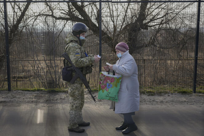Un soldat ukrainien vérifie les documents d’une femme souhaitant rejoindre la zone sous contrôle de l’armée ukrainienne depuis la zone tenue par les séparatistes prorusses, dans la région de Louhansk, le 22 février 2022.