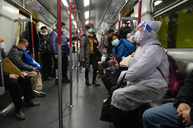 Une femme porte un masque, une visière et une combinaison pour se protéger du Covid-19, dans un train à Hongkong, le 23 février 2022.