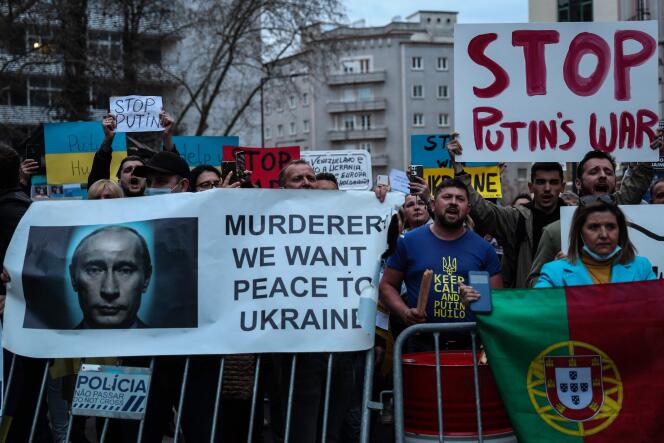 Manifestantes seguram uma faixa com os dizeres 'Assassino, queremos paz na Ucrânia' e 'Pare a guerra de Putin' durante um protesto contra a operação militar russa na Ucrânia, em frente à Embaixada da Rússia em Lisboa, Portugal, em 24 de fevereiro de 2022.