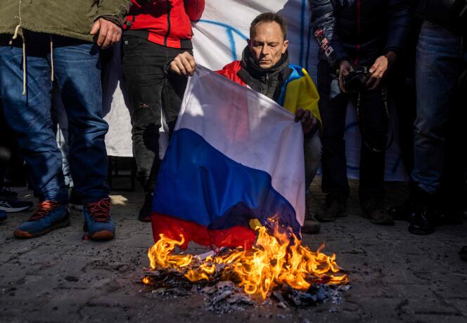 Un manifestant brûle un drapeau russe lors d'une manifestation contre l'invasion de l'Ukraine par la Russie, devant l'ambassade de Russie à Varsovie, en Pologne, le 24 février 2022.