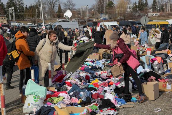 Des réfugiés ukrainiens se voient offrir des vêtements chauds à leur arrivée au poste frontière de Medyka, en Pologne, samedi 26 février 2022.