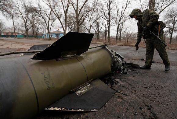 Un militant de la république autoproclamée de Donetsk inspecte les restes d’un missile qui a atterri dans une rue de la ville de Donetsk, contrôlée par les séparatistes, en Ukraine, le 26 février 2022.