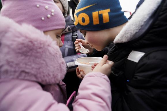 Un frère et une sœur partagent un bol de soupe après avoir fui avec leur mère l’invasion russe en Ukraine et traversé la frontière, à Medyka, en Pologne, le 26 février 2022.