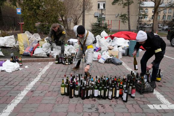 Des membres de la défense civile préparent des cocktails Molotov dans une cour à Kiev, Ukraine, dimanche 27 février 2022.