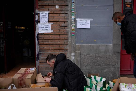 Un volontaire emballe des produits de première nécessité sous un panneau indiquant « Nous collectons de l’argent pour le gaz » dans le cadre d’une campagne de collecte pour soutenir les citoyens en Ukraine, devant le magasin Ukramarket à Madrid, le 27 février 2022.