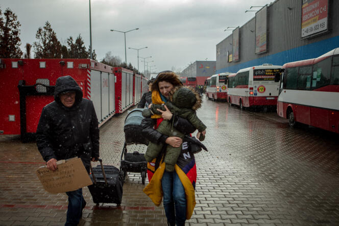 Une femme serre son enfant dans ses bras pour le protéger du froid et de la pluie, à Korczowa (Pologne), le 27 février 2022.