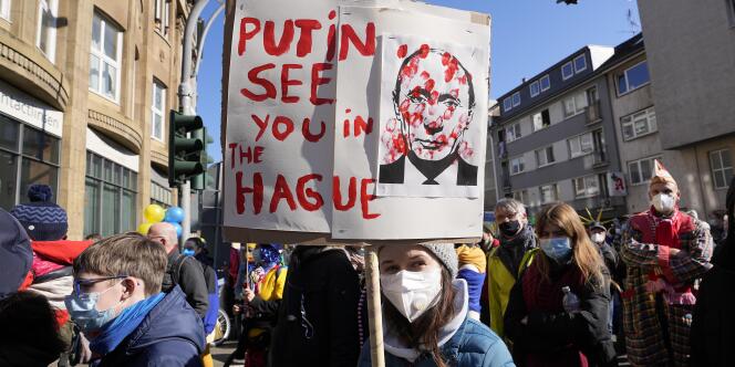 Une manifestante porte une pancarte indiquant « Poutine, on se voit à La Haye », lors d’un rassemblement en soutien à l’Ukraine, à Cologne, en Allemagne, le 28 février 2022.