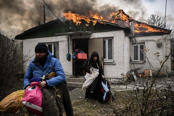 Des civils sortent leurs affaires d’une maison en feu après le bombardement de la ville d’Irpin, en banlieue de Kiev, le 4 mars 2022.