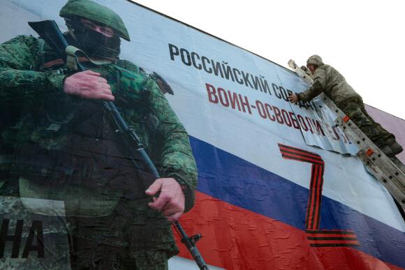 Un homme finit de coller une énorme pancarte représentant un soldat, sur laquelle on peut lire « Un soldat russe est un libérateur ! » dans le centre-ville de Simferopol, en Crimée, le 4 mars 2022.