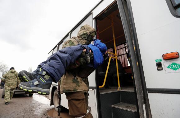 Un membre des troupes prorusses place un enfant évacué de Marioupol ou de ses environs dans un bus à destination du territoire russe, le 8 mars 2022.