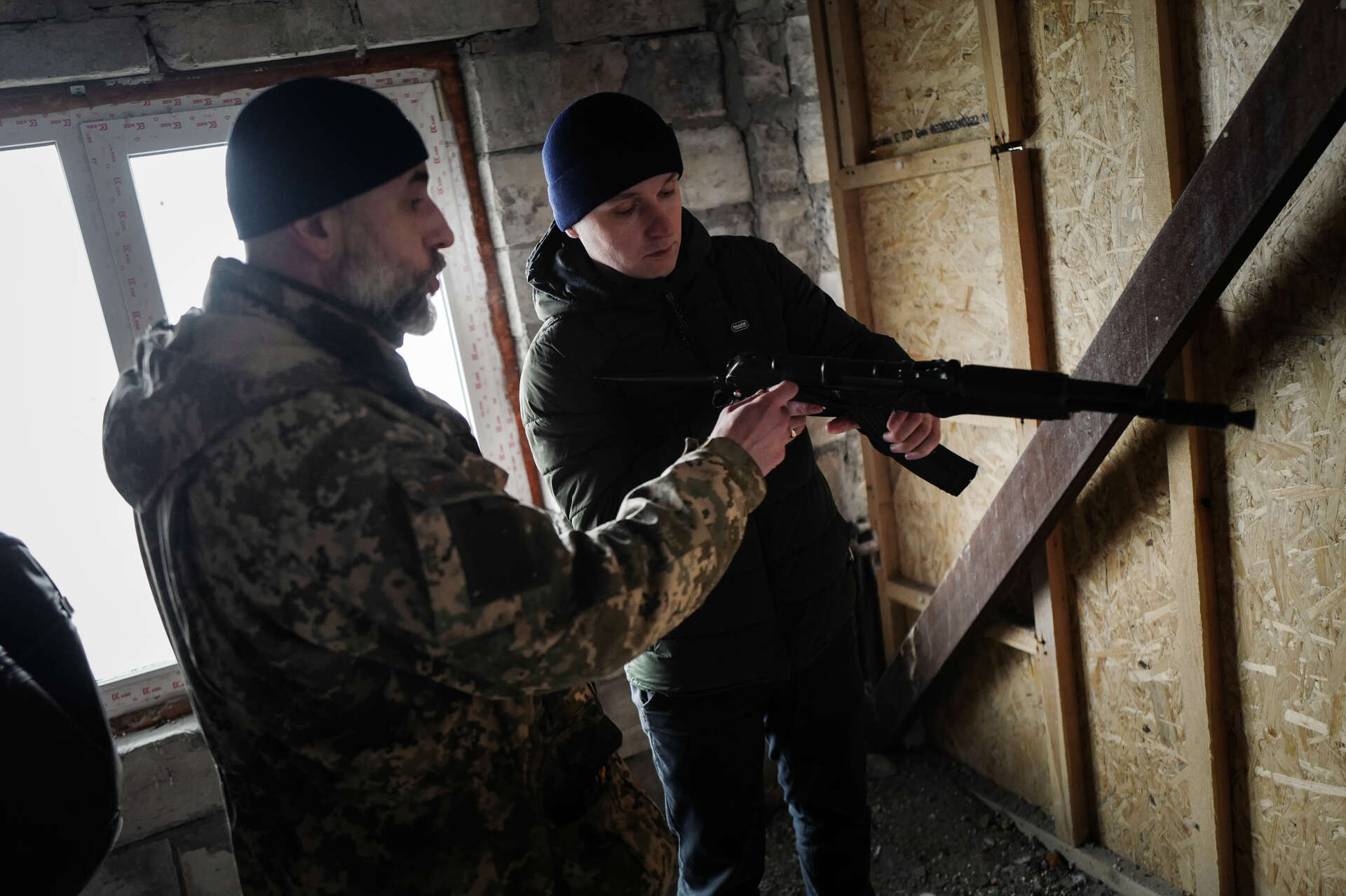 Un instructeur explique à un jeune civil comment charger un fusil d’assaut dans un entrepôt de Lviv (Ukraine), le 8 mars 2022.