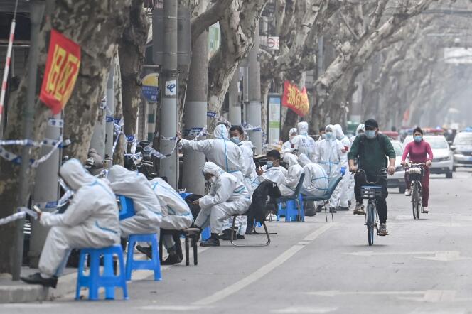 Des policiers et différents employés portent des vêtements de protection dans des zones confinées après la détection de nouveaux cas de Covid-19, à Shanghaï, le 14 mars 2022.