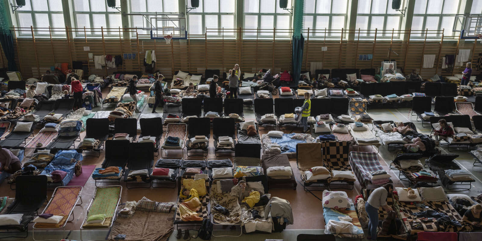 Des personnes ayant fui la guerre en Ukraine se reposent à l’intérieur d’un stade couvert utilisé comme centre de réfugiés, dans le village de Medyka, un poste frontière entre la Pologne et l’Ukraine, le mardi 15 mars 2022.