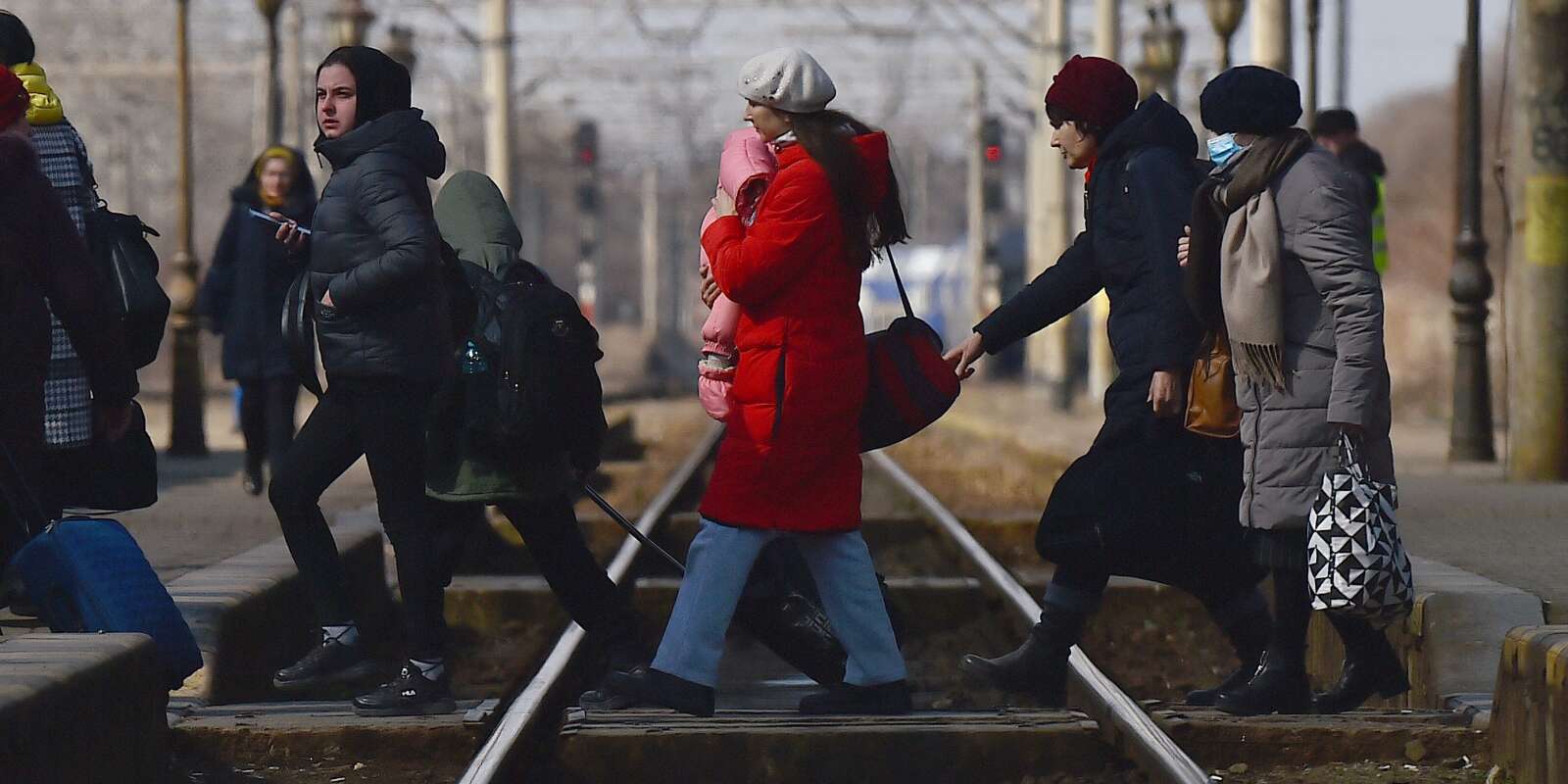 Une mère réfugiée tient son bébé dans ses bras alors qu’elles traversent les voies ferrées pour monter dans un train à destination de Bucarest à la gare de Suceava, après avoir fui l’Ukraine vers le poste frontière de Siret en Roumanie, suite à l’invasion de l’Ukraine par la Russie, à Suceava, en Roumanie, le 17 mars 2022.