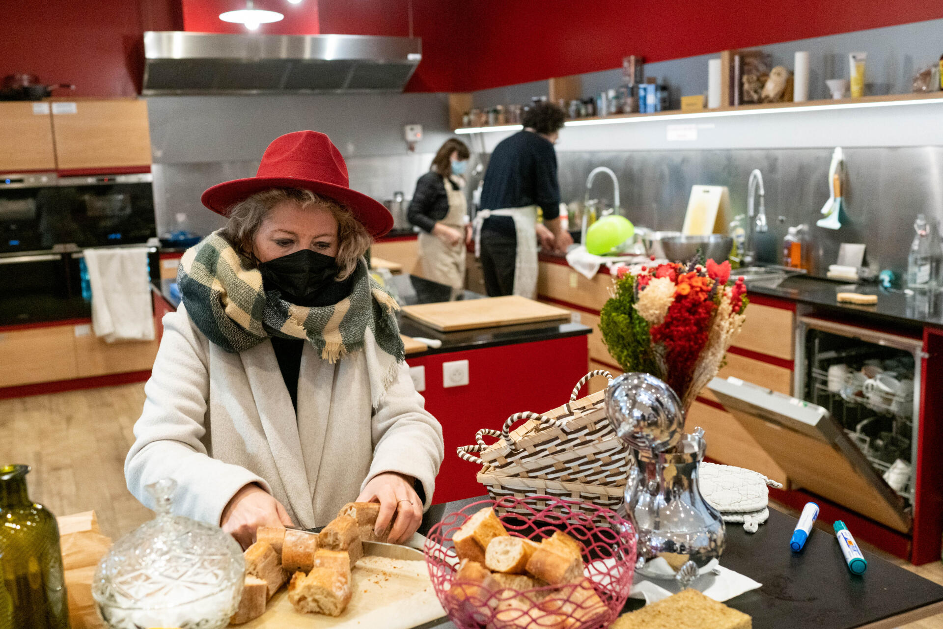Judith, membre du Club, coupe du pain pour le déjeuner à venir. Paris, le 2 mars 2022.