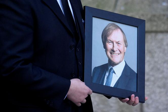 Un hombre sostiene un retrato del parlamentario David Amess, durante una misa conmemorativa en su honor, en Londres, el 23 de noviembre de 2021.