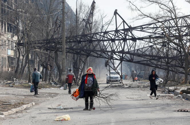Des habitants ramassent du bois dans un quartier détruit de Marioupol, en Ukraine, le 25 mars 2022. 