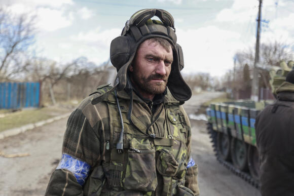 Un militaire ukrainien se tient dans une rue du village de Loukianivka, à l’est de Kiev, Ukraine, dimanche 27 mars 2022.