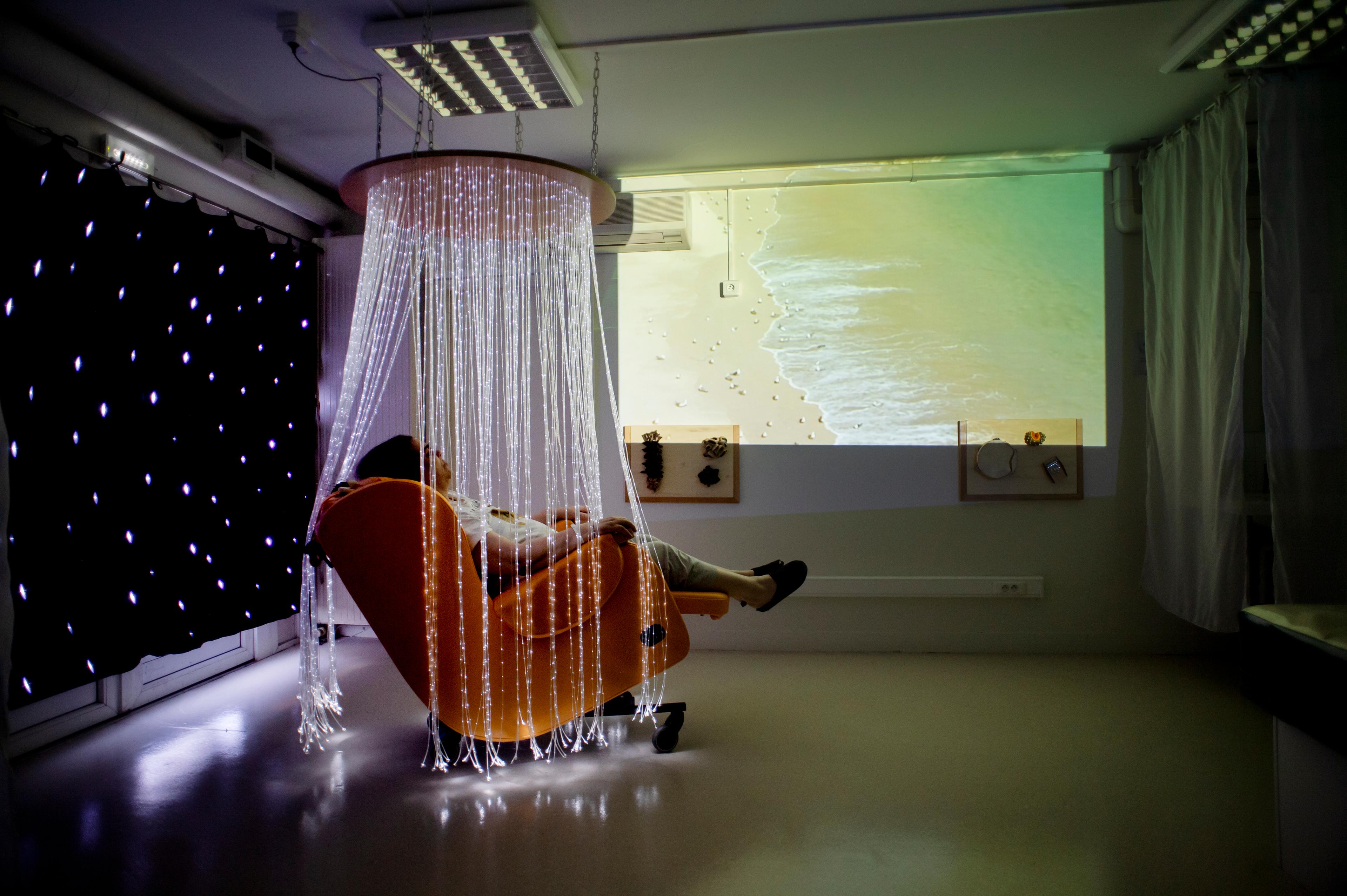 Une résidente se détend selon la pratique du Snoezelen, une activité vécue dans un espace spécialement aménagé, avec lumière tamisée et musique douce, afin de recréer une ambiance agréable, le 25 mars 2022.