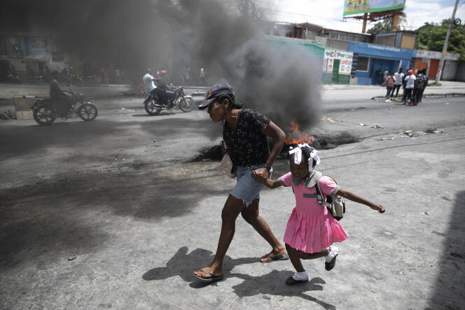A woman guides a child past a demonstration against increasing violence, in the middle of a spike in gang-related kidnappings, in Port-au-Prince, March 29, 2022.