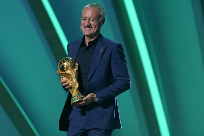 Le sélectionneur de l’équipe de France, Didier Deschamps, porte le trophée de la Coupe du monde, lors du tirage au sort du mondial 2022, le 1er avril 2022, à Doha (Qatar).