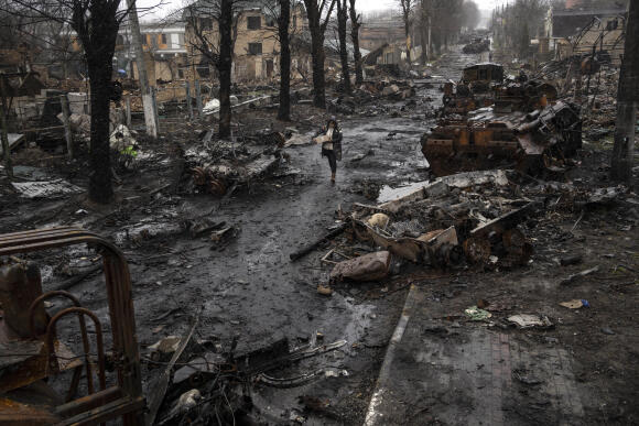 Une femme marche au milieu de chars russes détruits à Boutcha, dans la banlieue de Kiev, en Ukraine, dimanche 3 avril 2022.