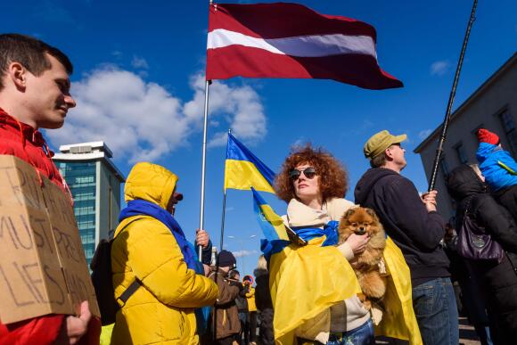 Des manifestants tiennent des drapeaux de la Lettonie et de l'Ukraine alors qu'ils manifestent en soutien à l'Ukraine le 3 avril 2022 à Daugavpils, une ville du sud-est de la Lettonie, dont la population est majoritairement russophone, située près des frontières avec la Biélorussie et la Lituanie.