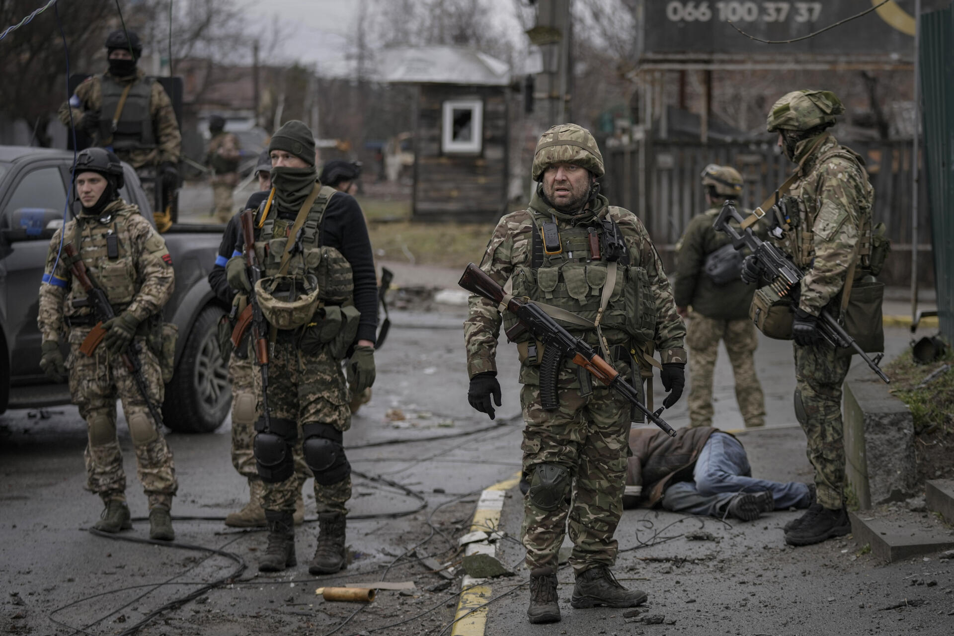Ukrainian soldiers stand next to the body of a man dressed in civilian clothes, in Boutcha, a suburb of Kiev, occupied by the Russians, before being liberated, in Ukraine, Saturday, April 2, 2022.