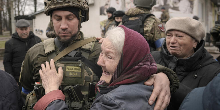 A woman hugs a Ukrainian serviceman after a convoy of military and aid vehicles arrived in the formerly Russian-occupied Kyiv suburb of Bucha, Ukraine, Saturday, April 2, 2022. As Russian forces pull back from Ukraine's capital region, retreating troops are creating a 