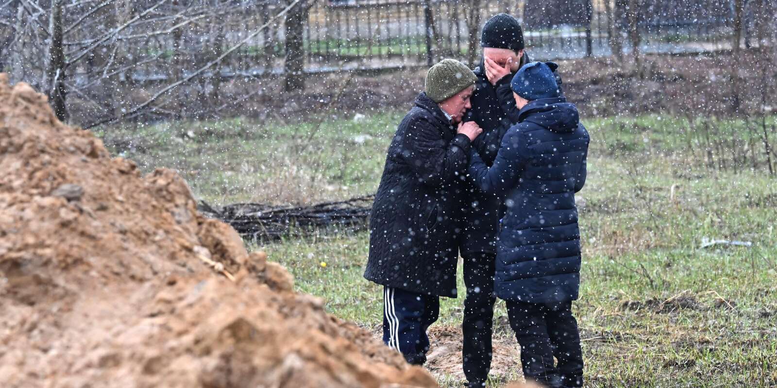 Des gens accablés de chagrin, à côté d’une fosse commune dans la ville de Boutcha, au nord-ouest de la capitale ukrainienne Kiev, le 3 avril 2022.