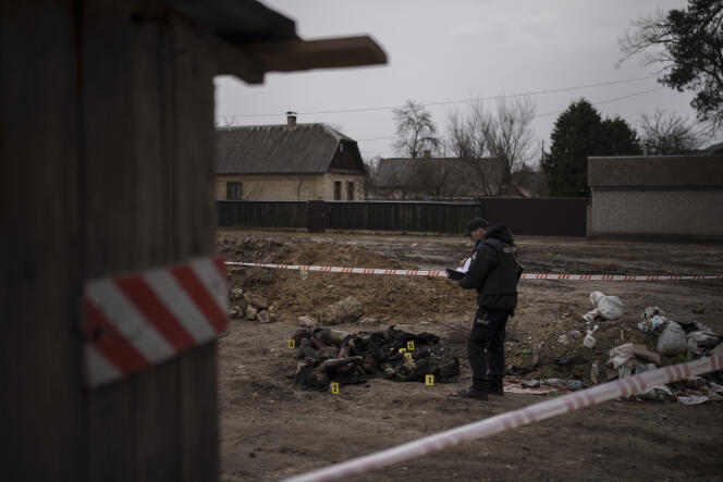 A police officer investigates the presence of six unidentified charred bodies in a residential area in Boutcha, northwest of Kiev, on April 5, 2022.