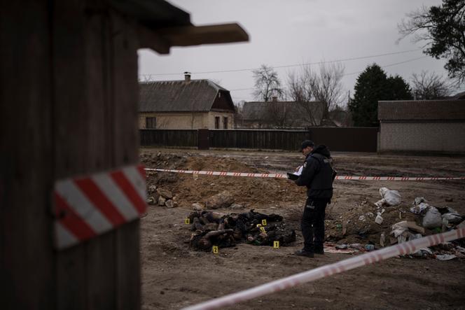 A police officer investigates the presence of six unidentified charred bodies in a residential area in Boutcha, northwest of Kiev, on April 5, 2022.