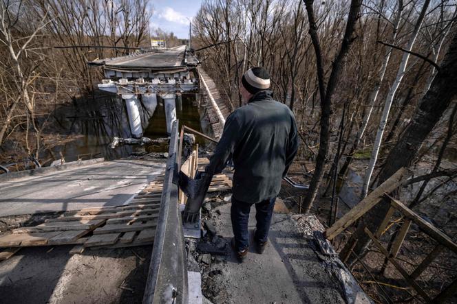 A man stands in front of a destroyed bridge near the village of Bohorodychne in the Donbas region on April 5, 2022.